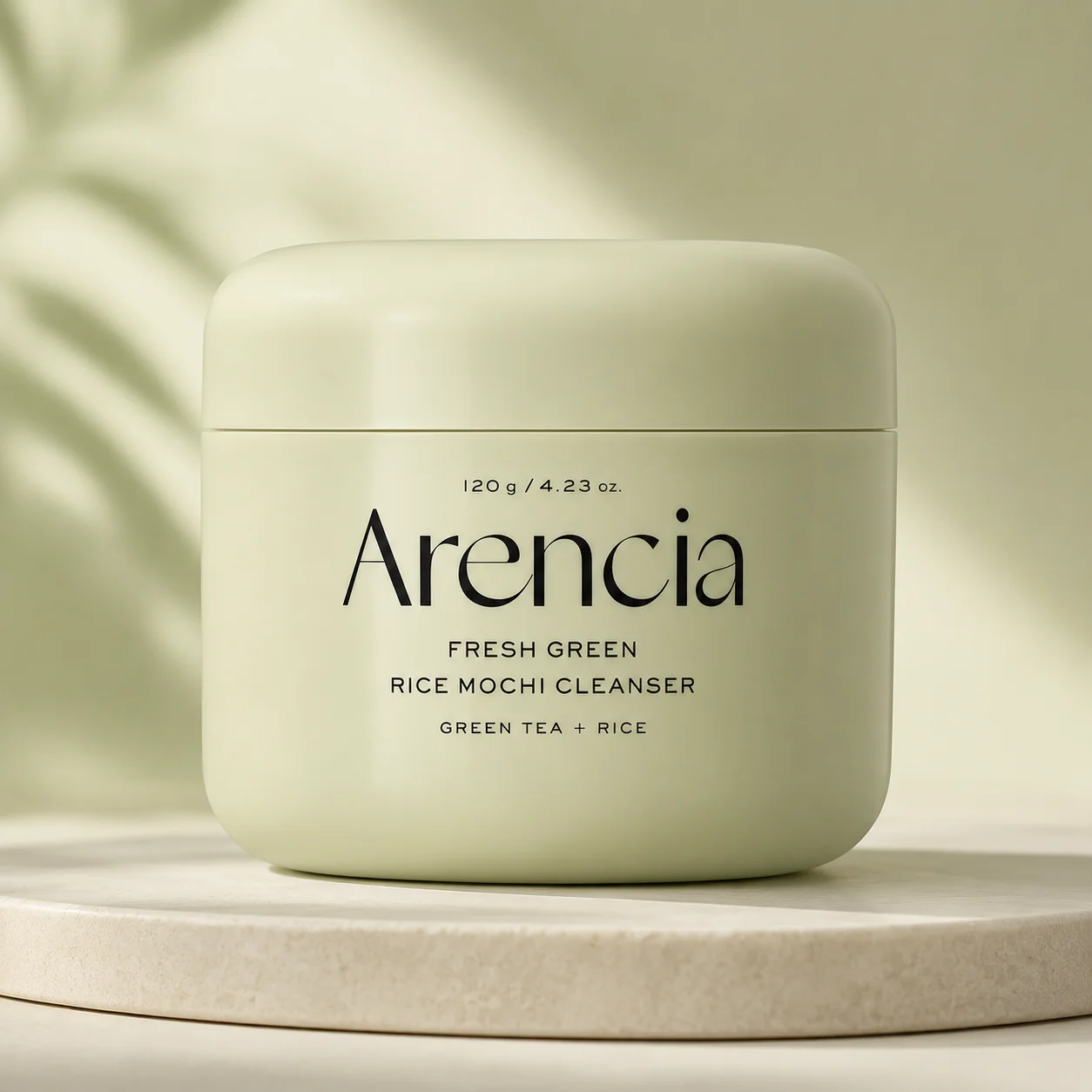 A light green container of Arencia Fresh Green Rice Mochi Cleanser featuring green tea and rice placed on a smooth stone surface.